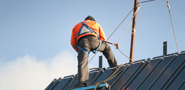 Worker on roof using fall protection harness during safety training